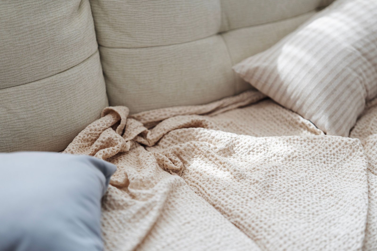 A comfortable beige couch with soft pillows and a textured blanket in a relaxed setting.