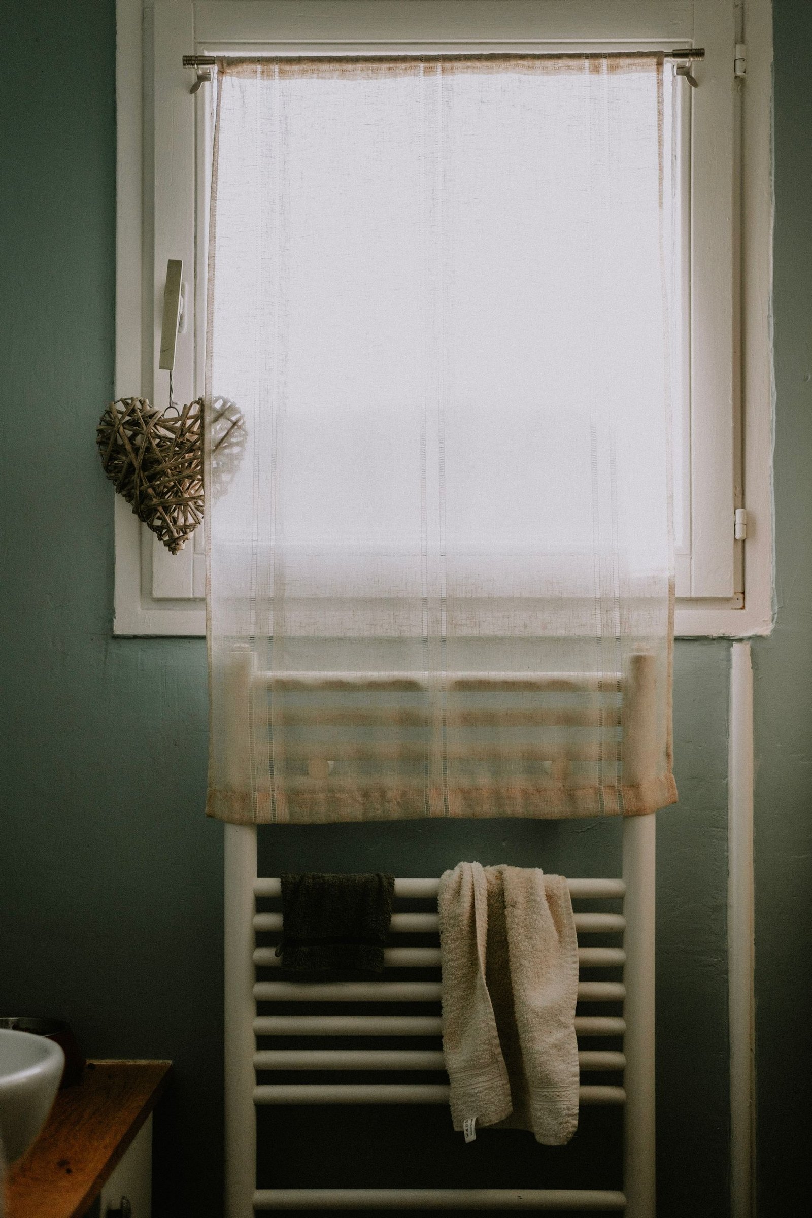 A cozy bathroom with heart-shaped decor and towels hanging on a rack by the window.