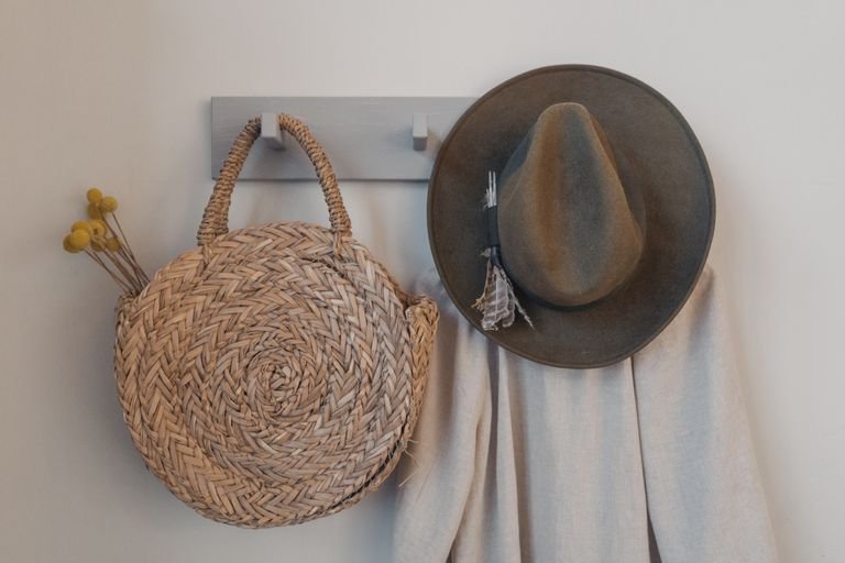 Adhesive hooks holding bags and clothes in a small rented bedroom.