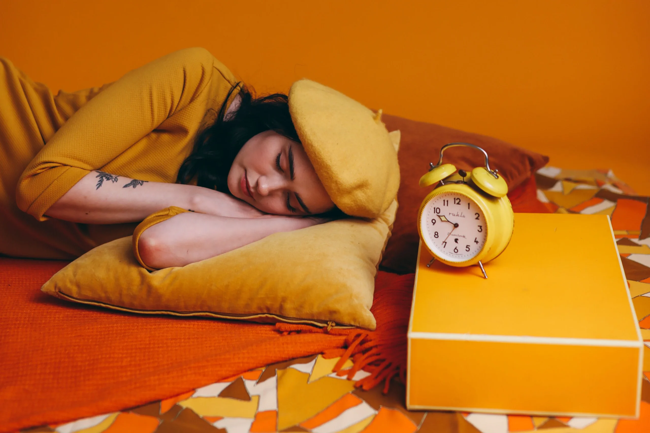 A woman sleeping in bed beside a yellow analog alarm clock — 10. if you wake, no clock-watching