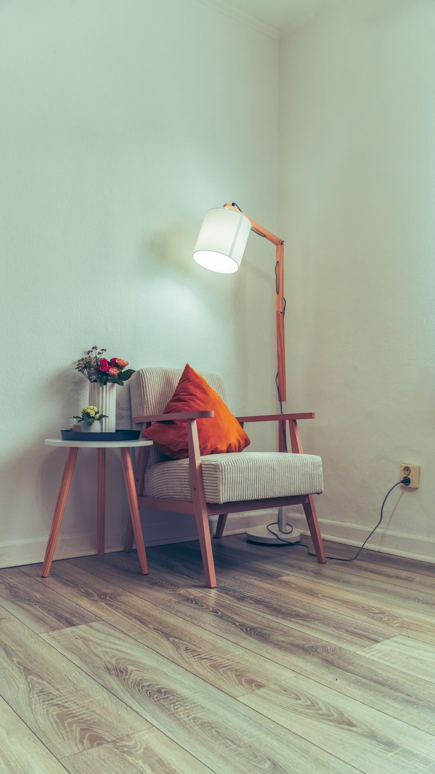 Inviting corner with a mid-century armchair, colorful pillow, and warm lamp light