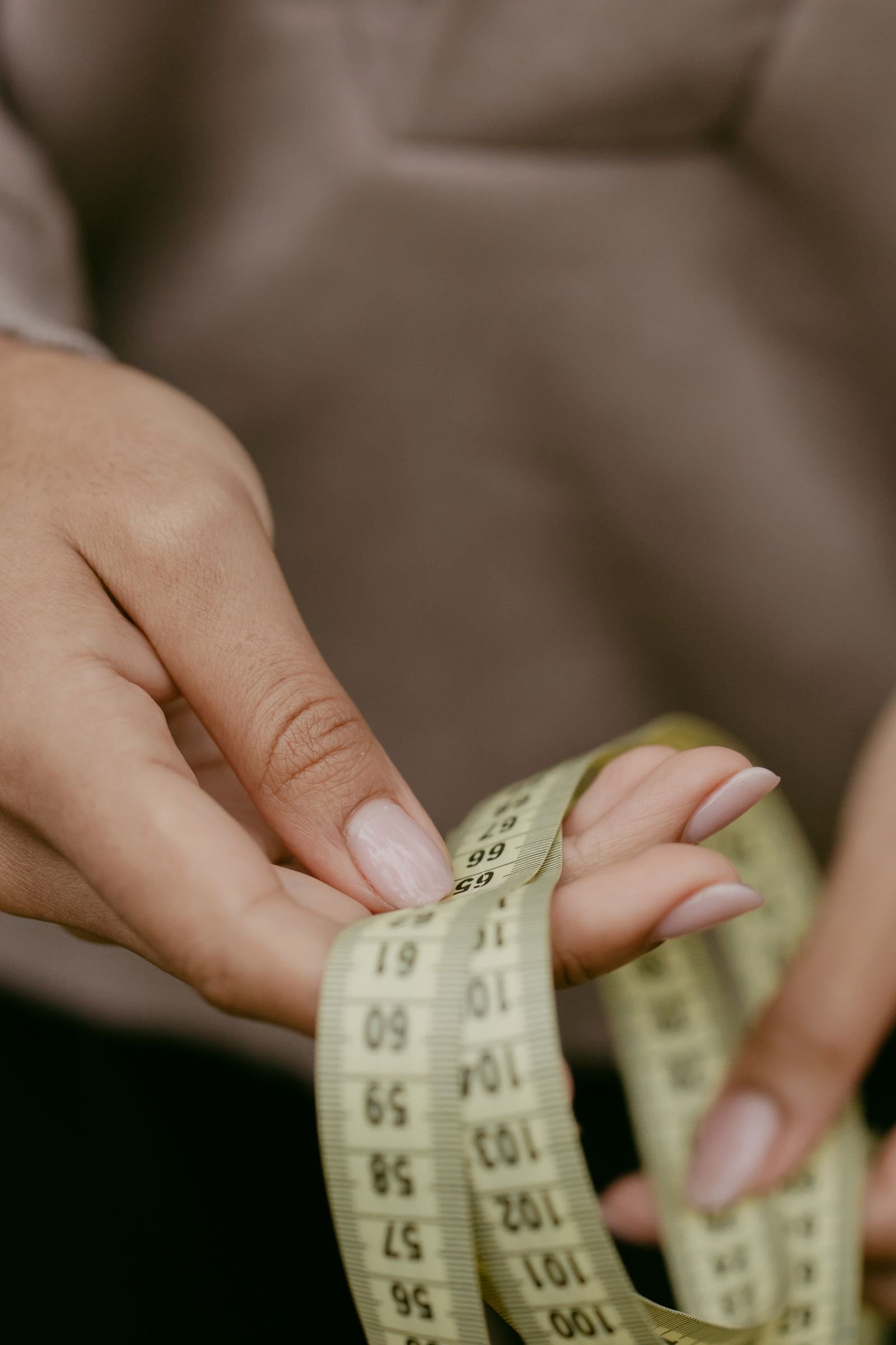 Hands holding a measuring tape — measure the seating wall before buying furniture