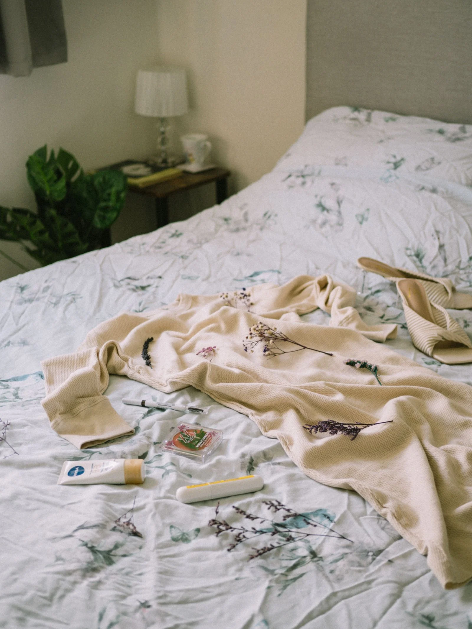 Floral dress and accessories laid out on a patterned bed in a cozy bedroom — laying out tomorrow's outfit for a calm small bathroom morning