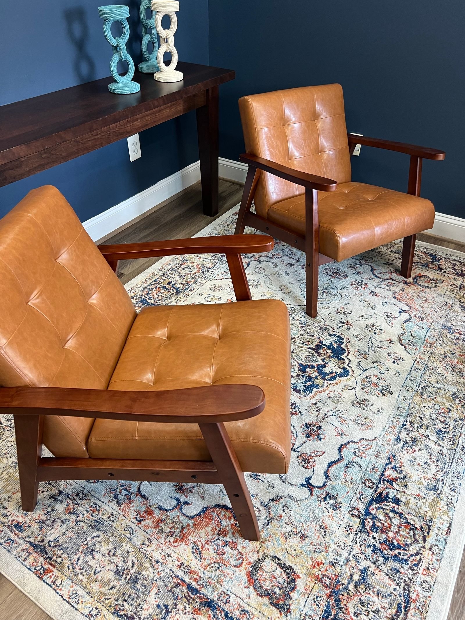 Two slim mid-century modern leather chairs on a patterned rug — armless slim-arm chairs save space