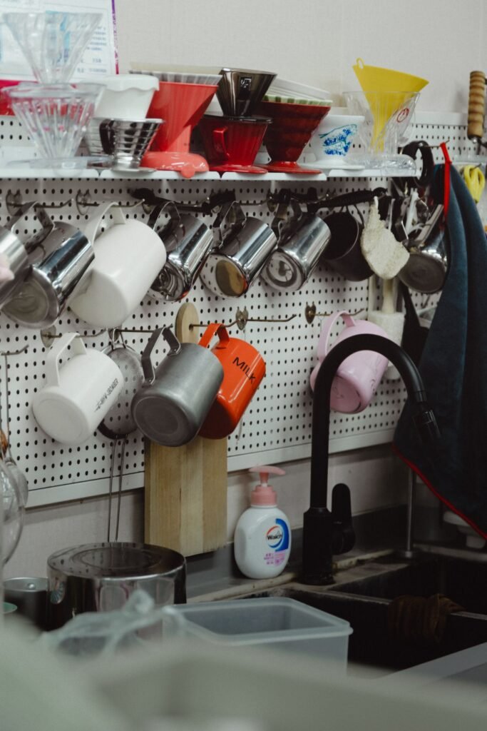 Neatly arranged kitchen pegboard with coffee mugs, kitchen items and small shelves — pegboard storage