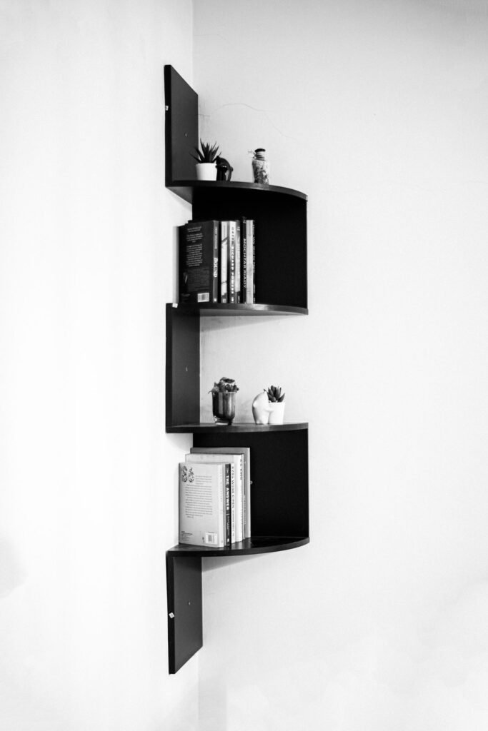 Black corner shelf styled with books and decor in a monochrome interior — vertical storage ideas