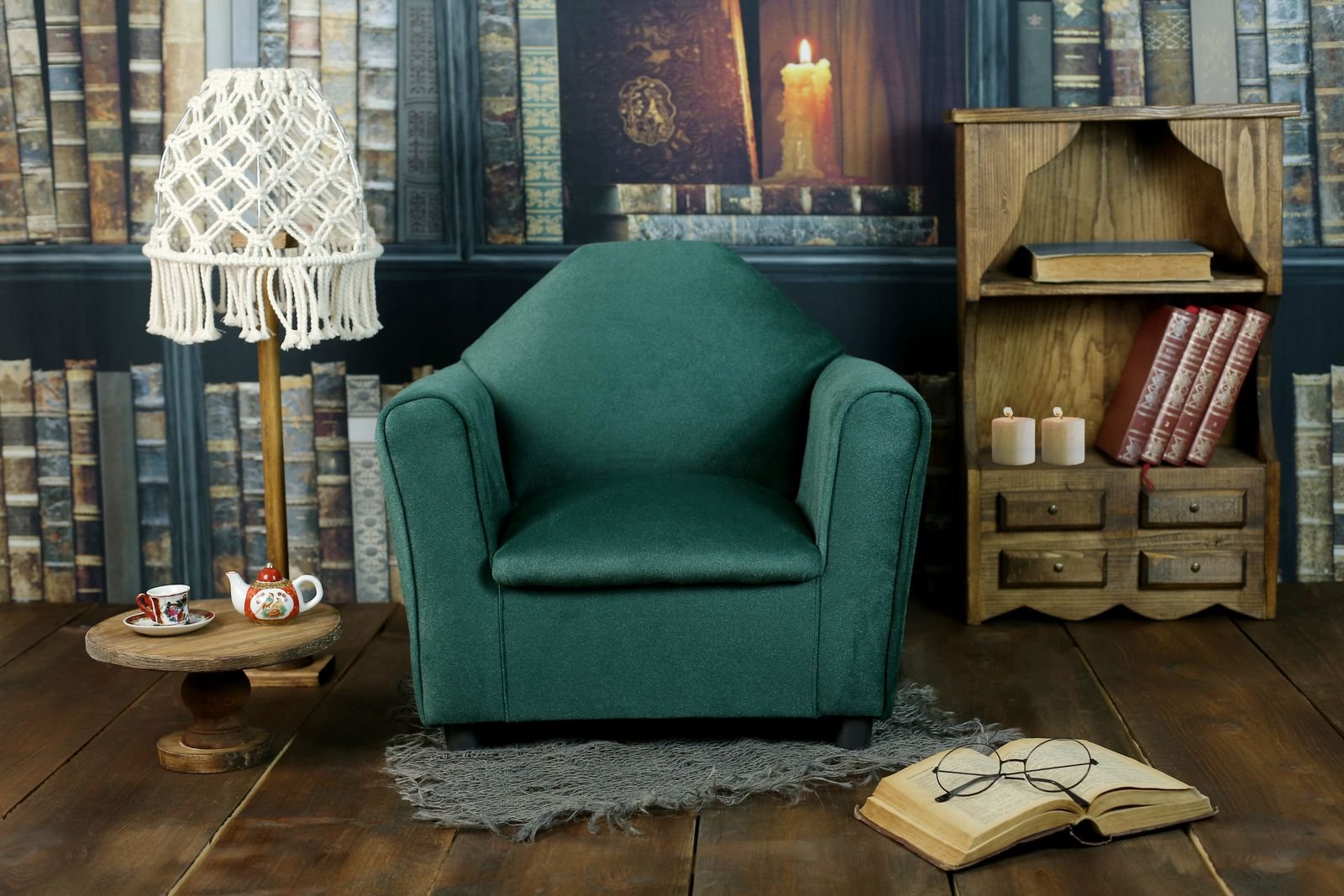 Green armchair beside a wooden bookshelf in a warm reading corner
