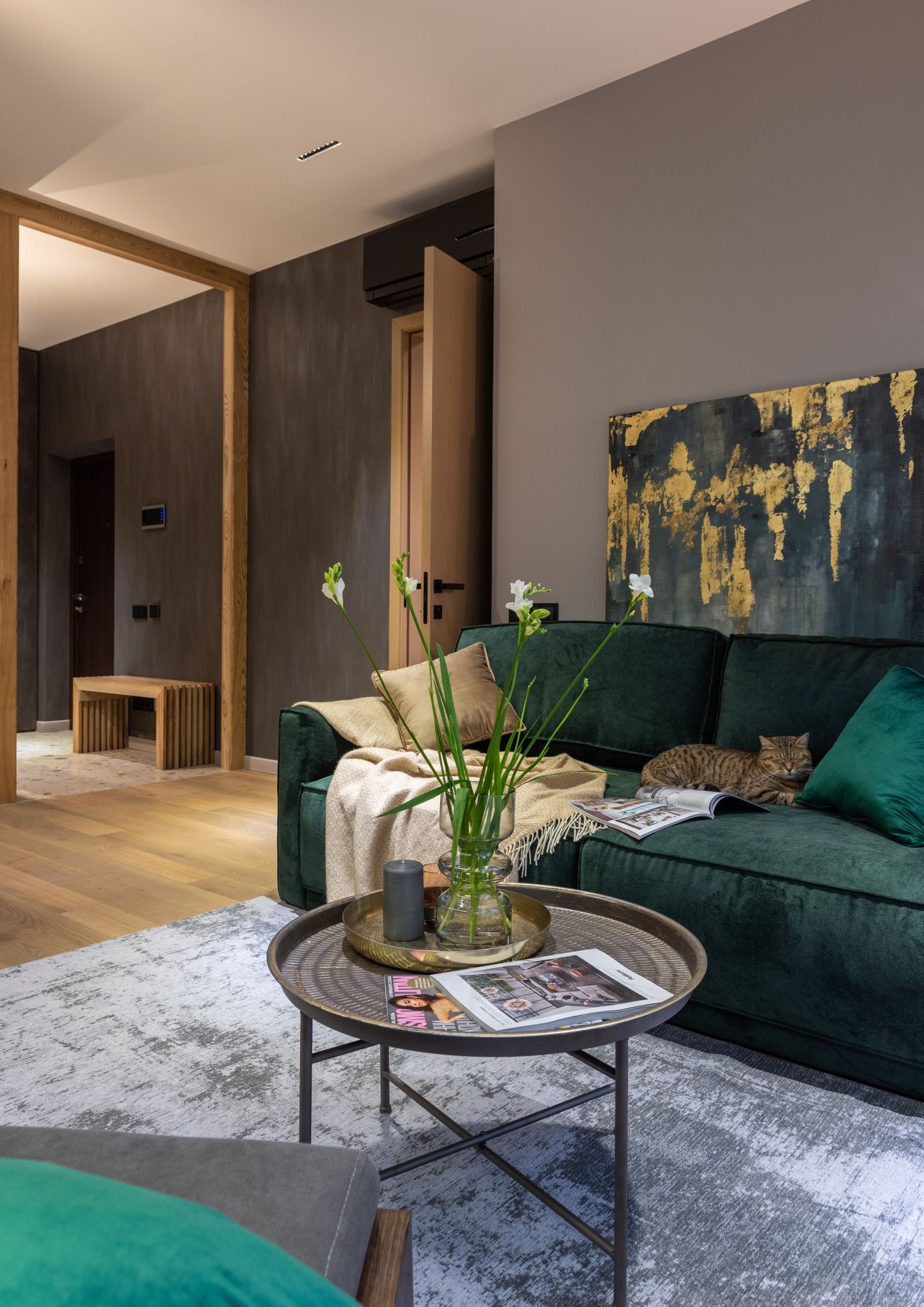 Round coffee table with flowers near a green sofa — keep the coffee table reachable from every seat