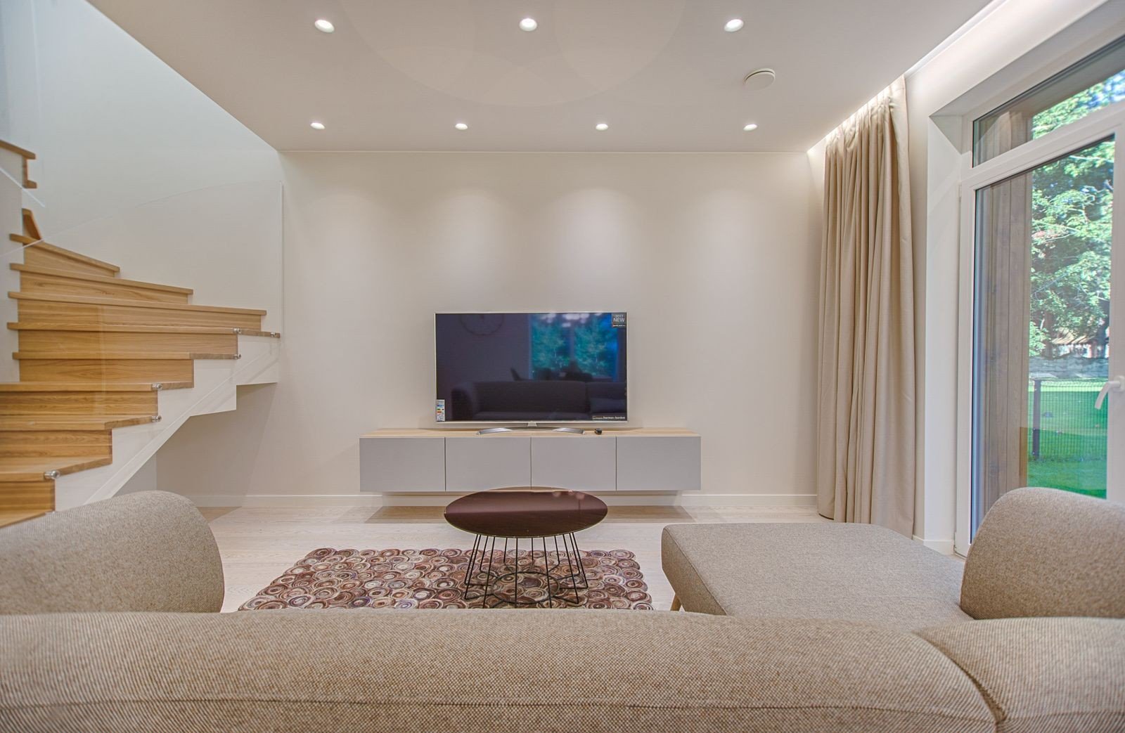 Contemporary living room with a stylish sofa facing a wall-mounted TV — one clear focal point in a small space