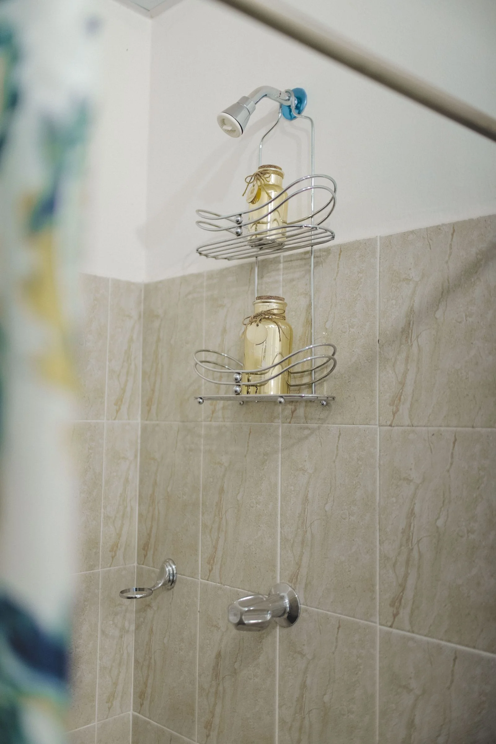 Vertical shower view with a wire shelf holding jars against tiled walls — organised shower storage for a small bathroom shower