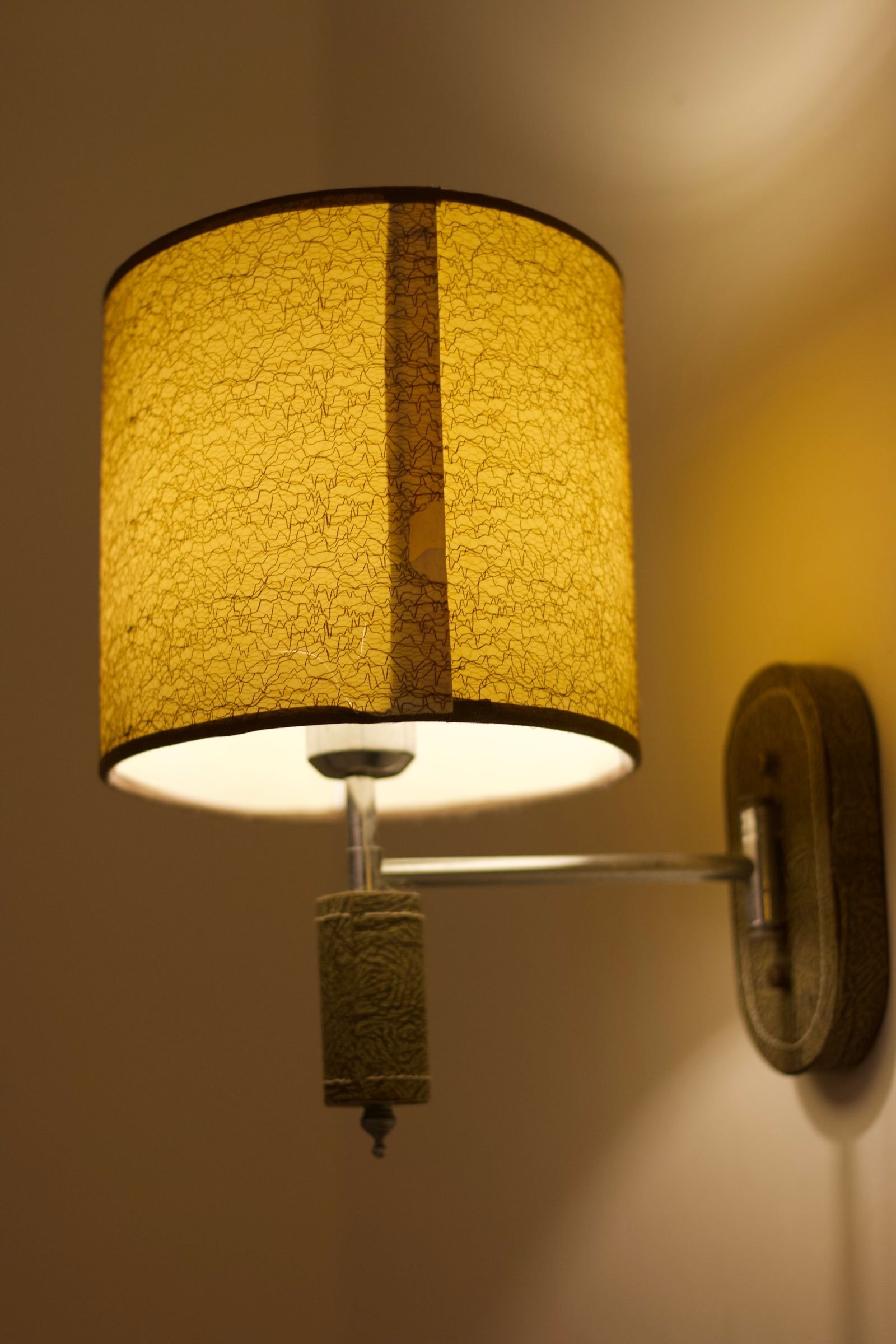 Wall-mounted lamp with textured shade glowing warmly in a cozy room