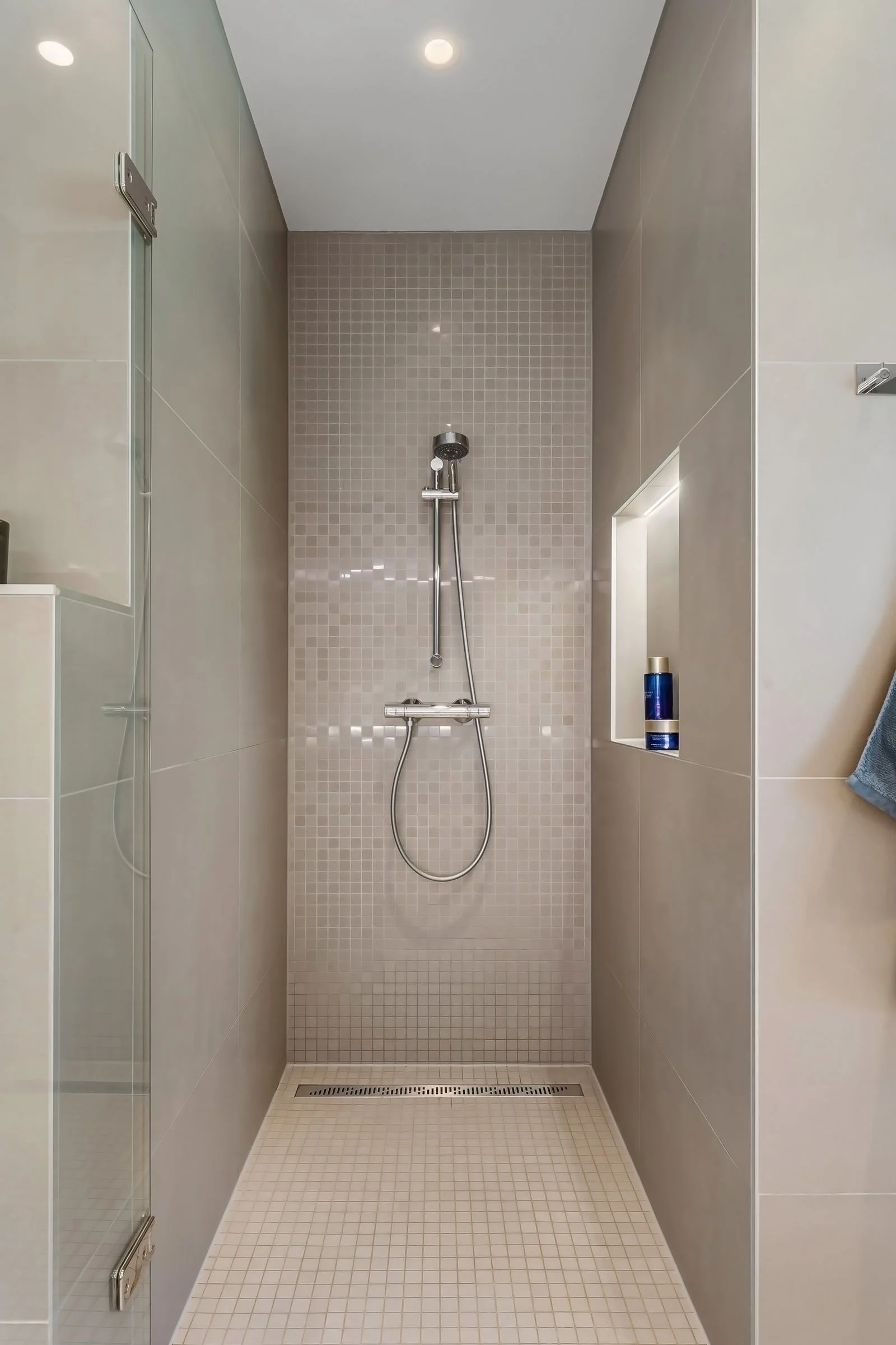 Contemporary shower with glass and tiled surfaces in a minimalist bathroom — a modern shower upgrade for a small bathroom