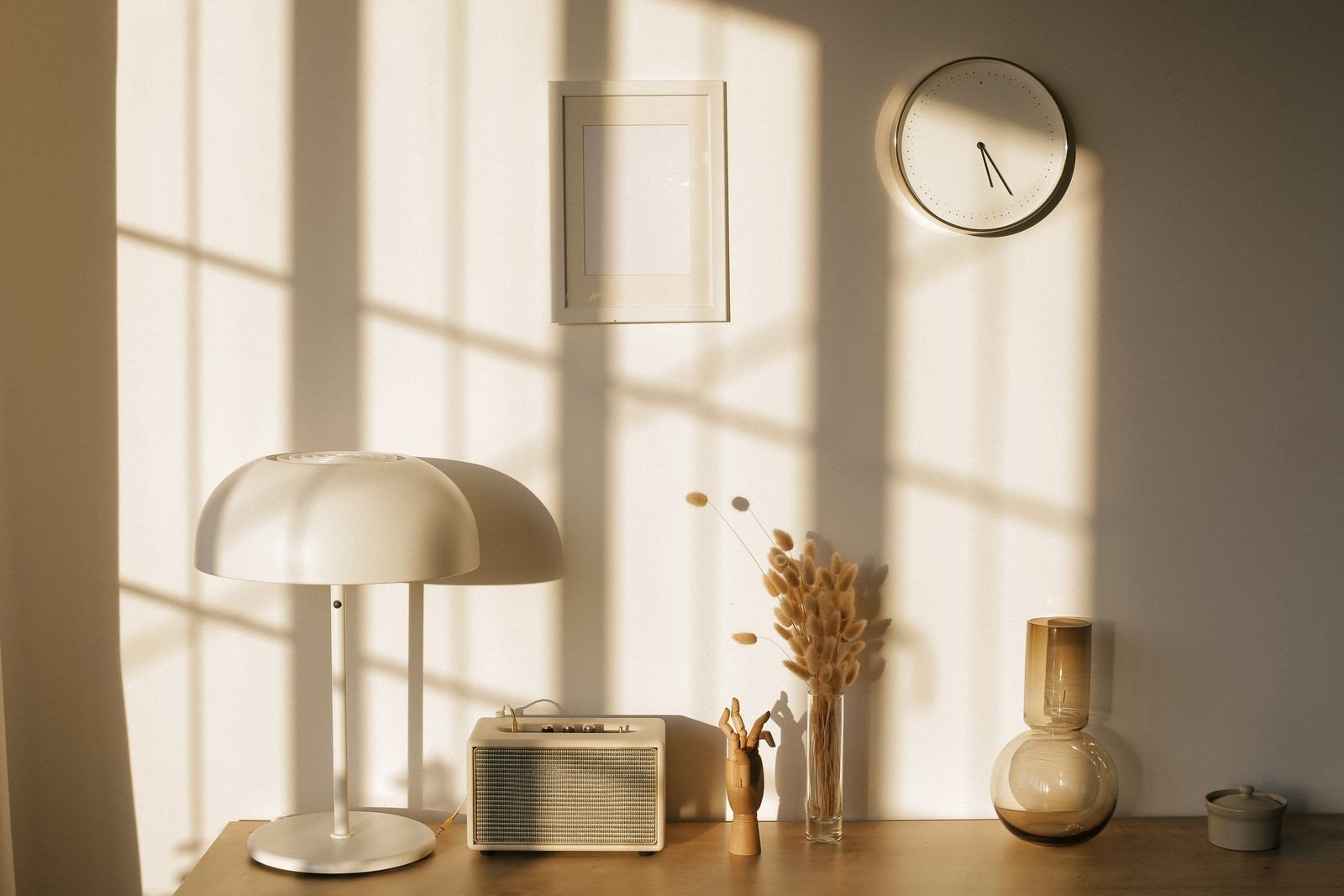 Sunlit styled tabletop with a vintage radio, vases and a small lamp — kept to just a few pieces