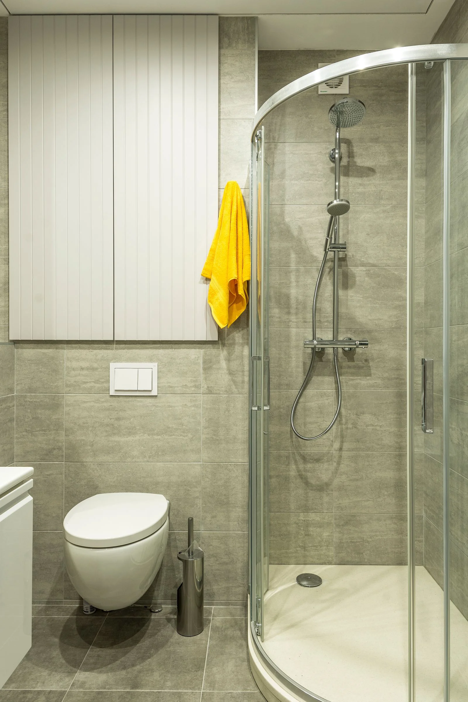 Bright modern bathroom with a shower cabin, toilet and yellow towel — a clean small bathroom shower area