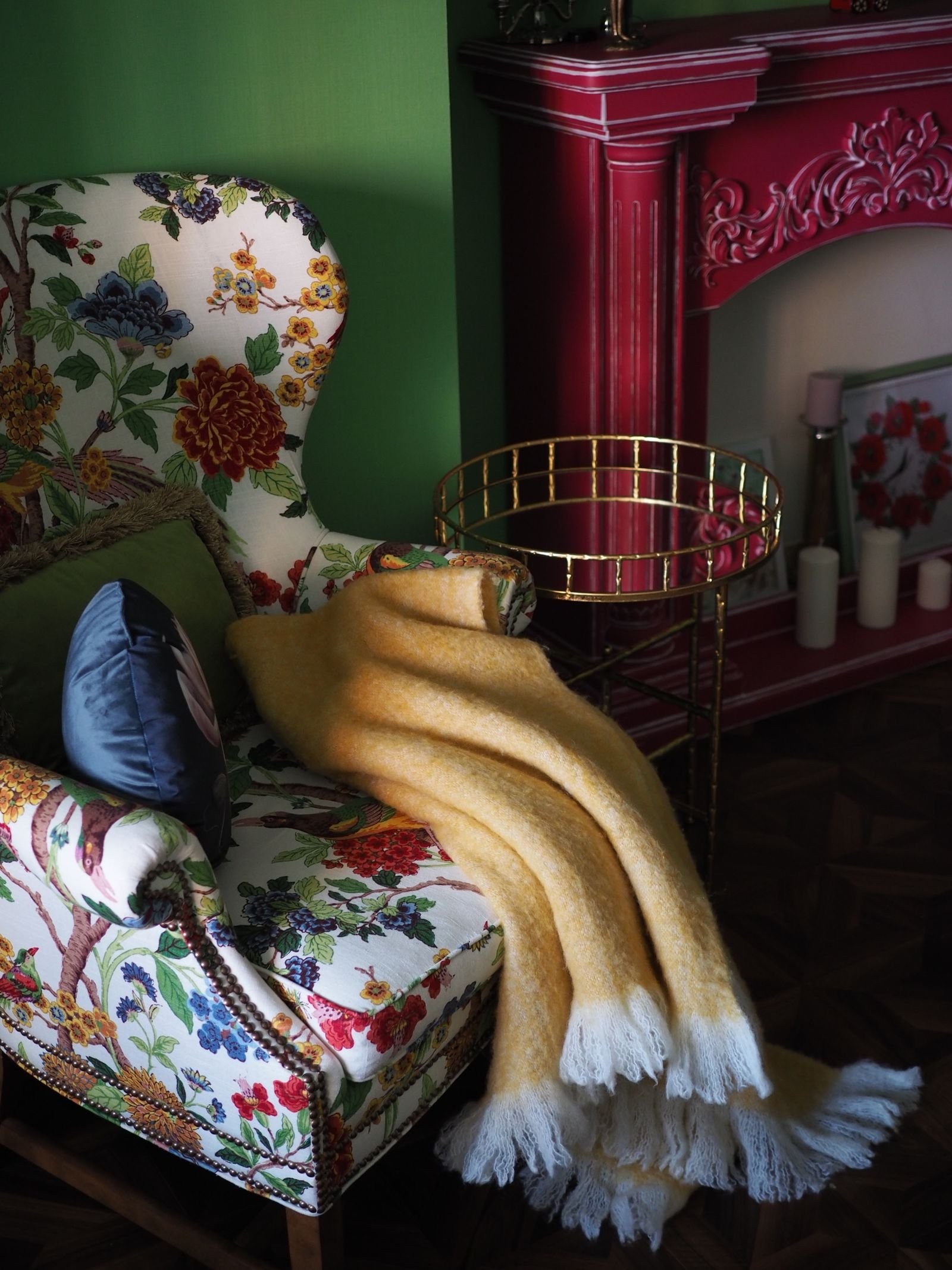 Floral armchair indoors with a soft yellow throw blanket draped over the seat