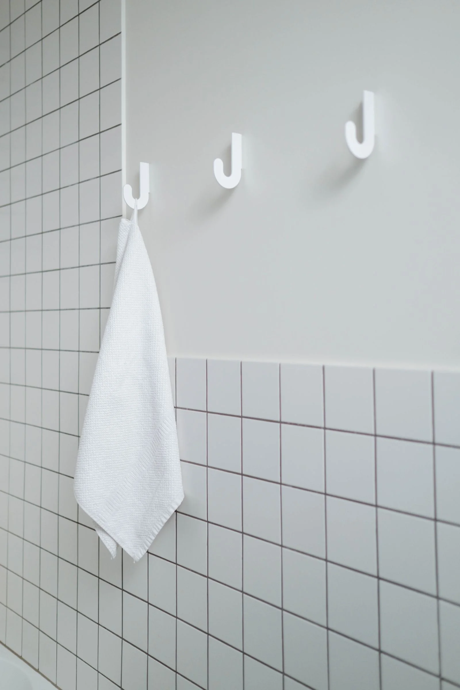 Clean minimalist bathroom with a white towel hanging on hooks — a towel hook idea for a small bathroom shower