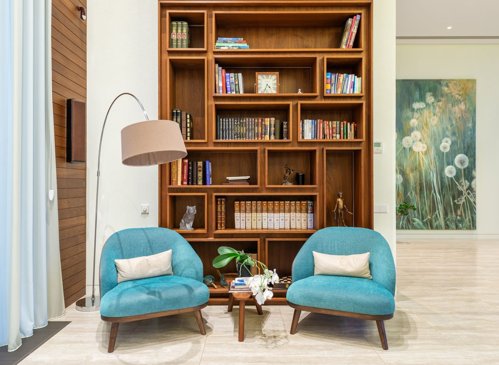 Inviting reading corner with armchairs beside a lamp and wooden bookcase