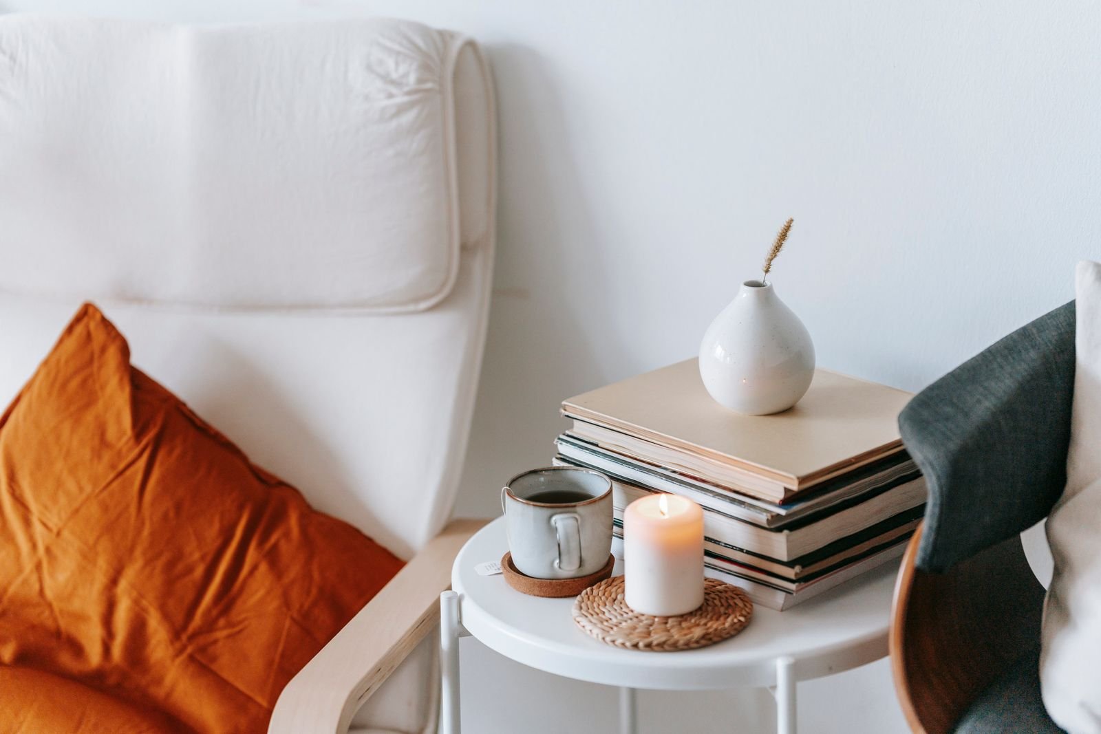 Lit candle and cup of tea on a table between two armchairs