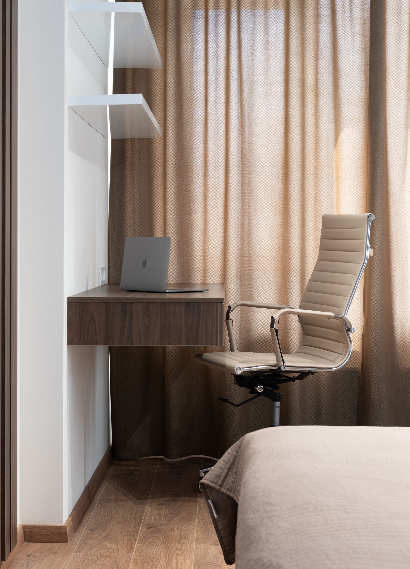 Corner desk with laptop and beige chair in a tidy apartment