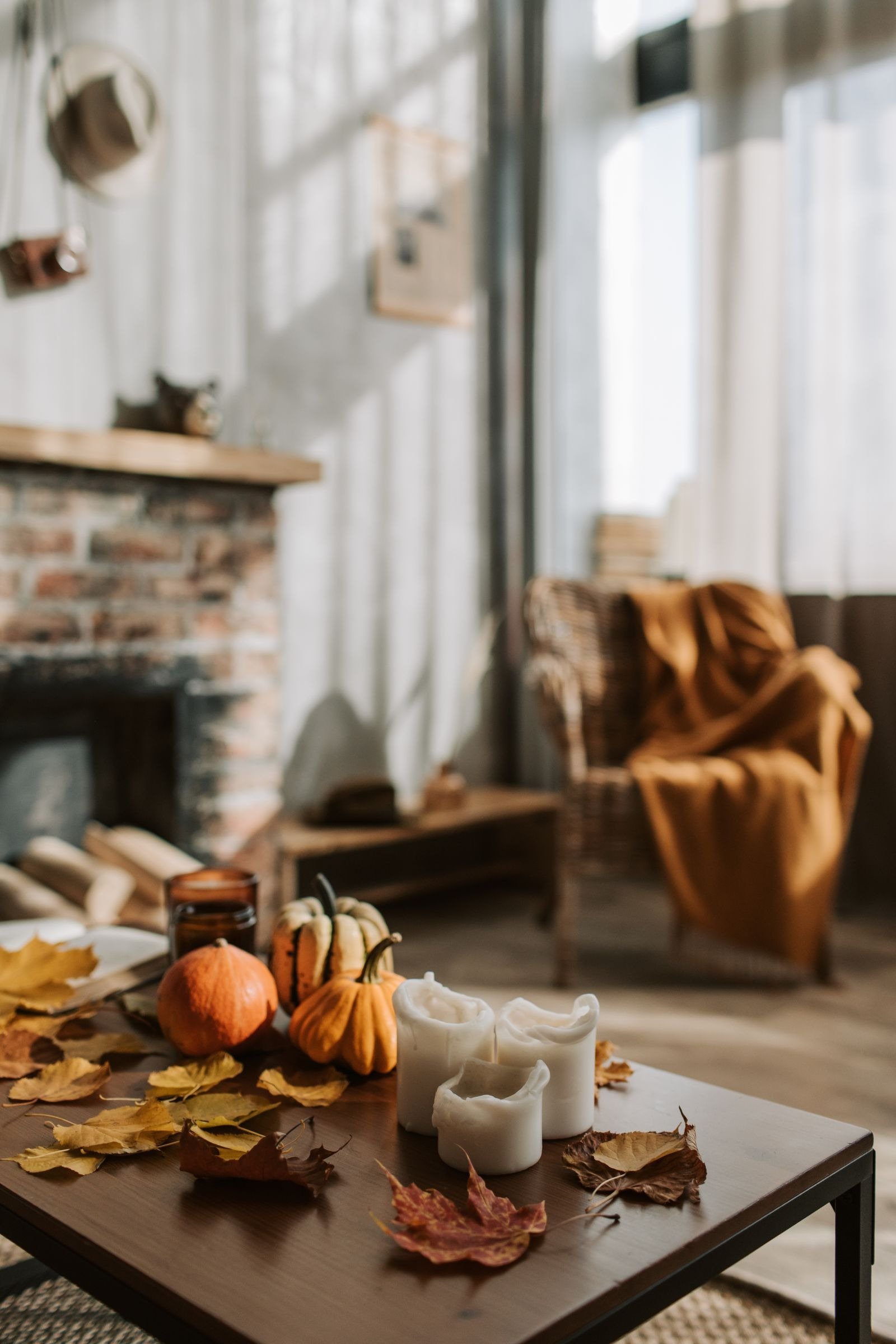 Autumn living room with pumpkins, dried leaves, candles, and an amber throw on an armchair