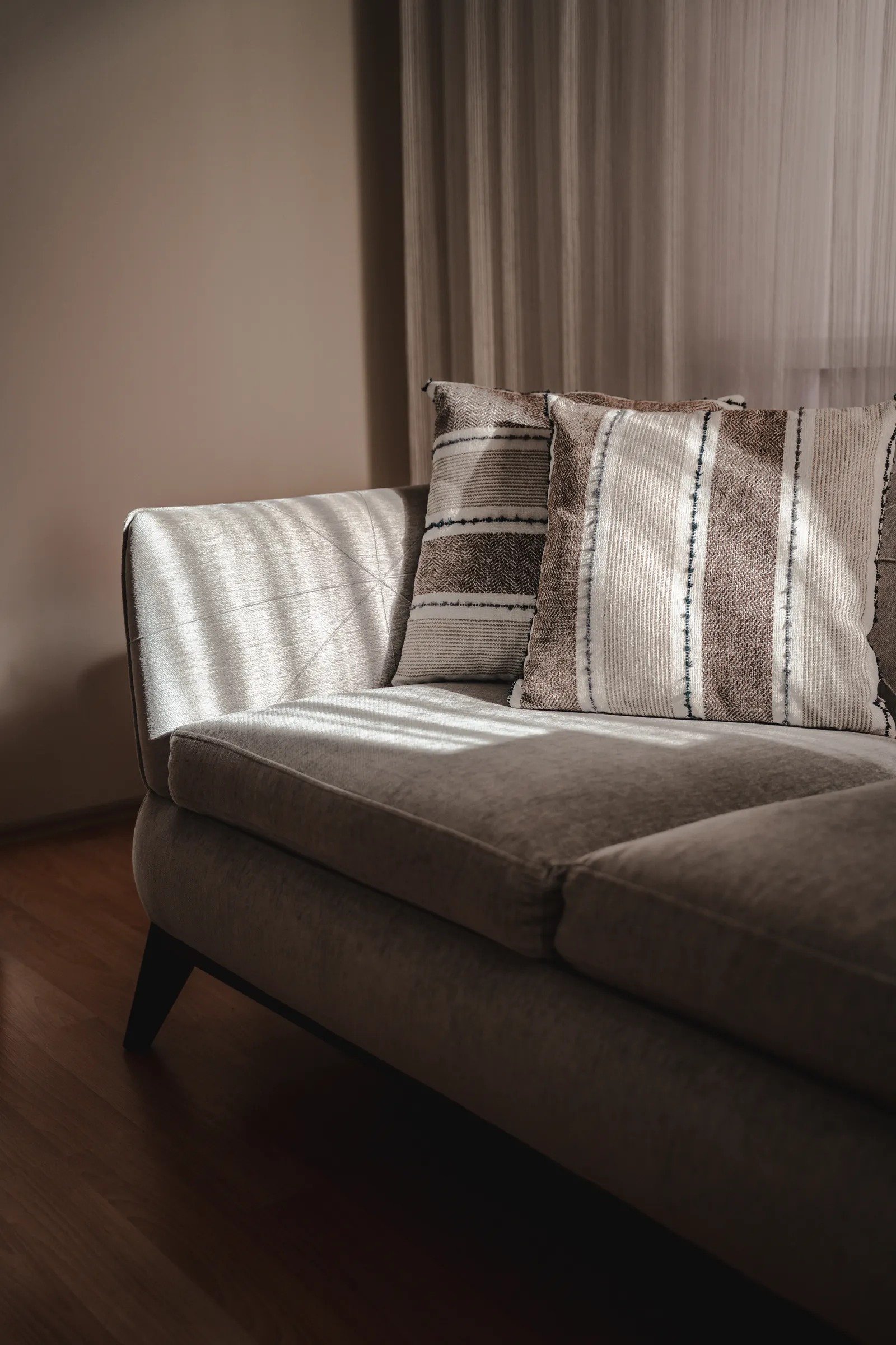 Grey sofa styled with two matching striped cushions in soft window light