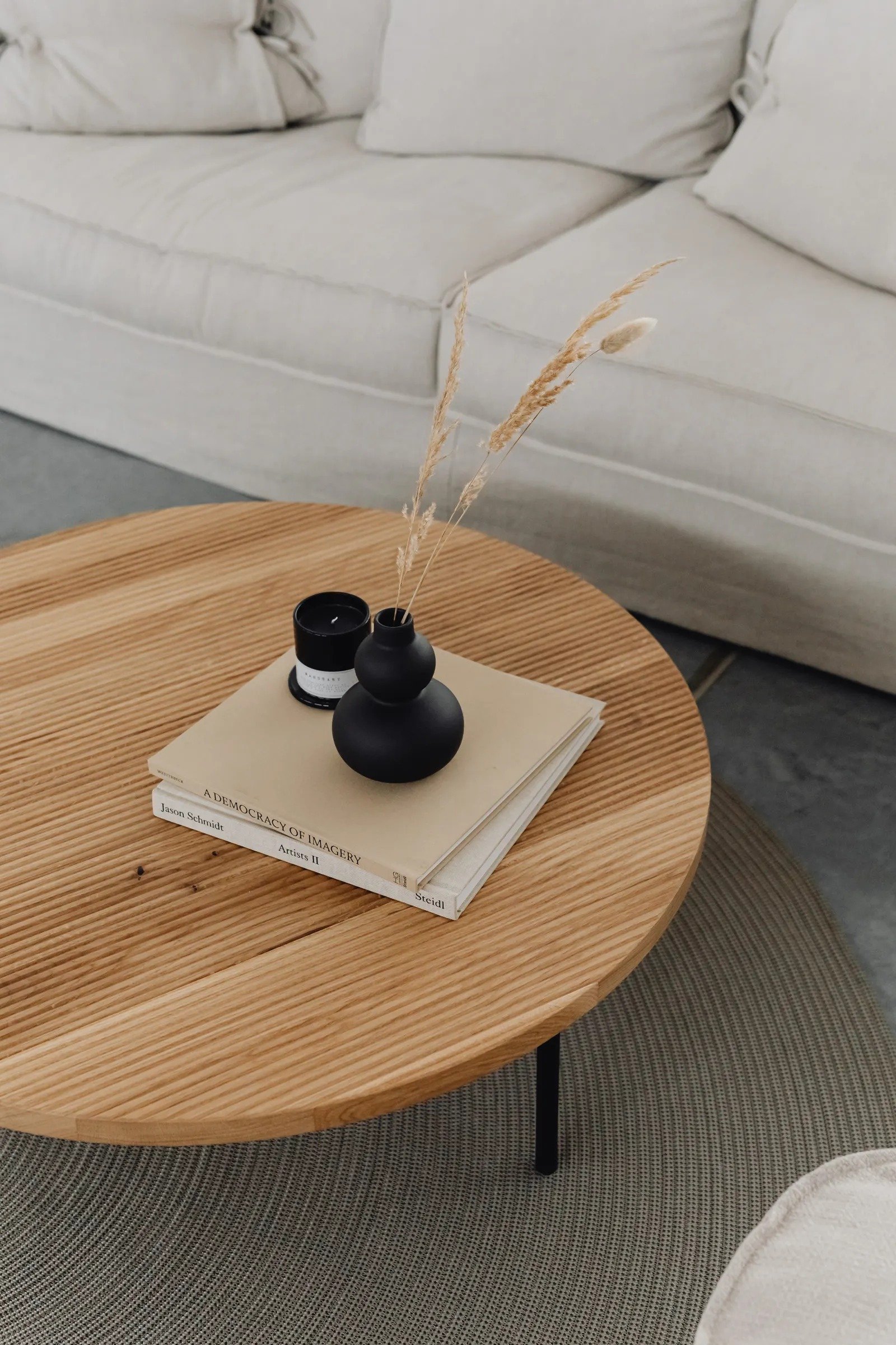 Wooden coffee table kept mostly clear with two stacked books and a small black vase