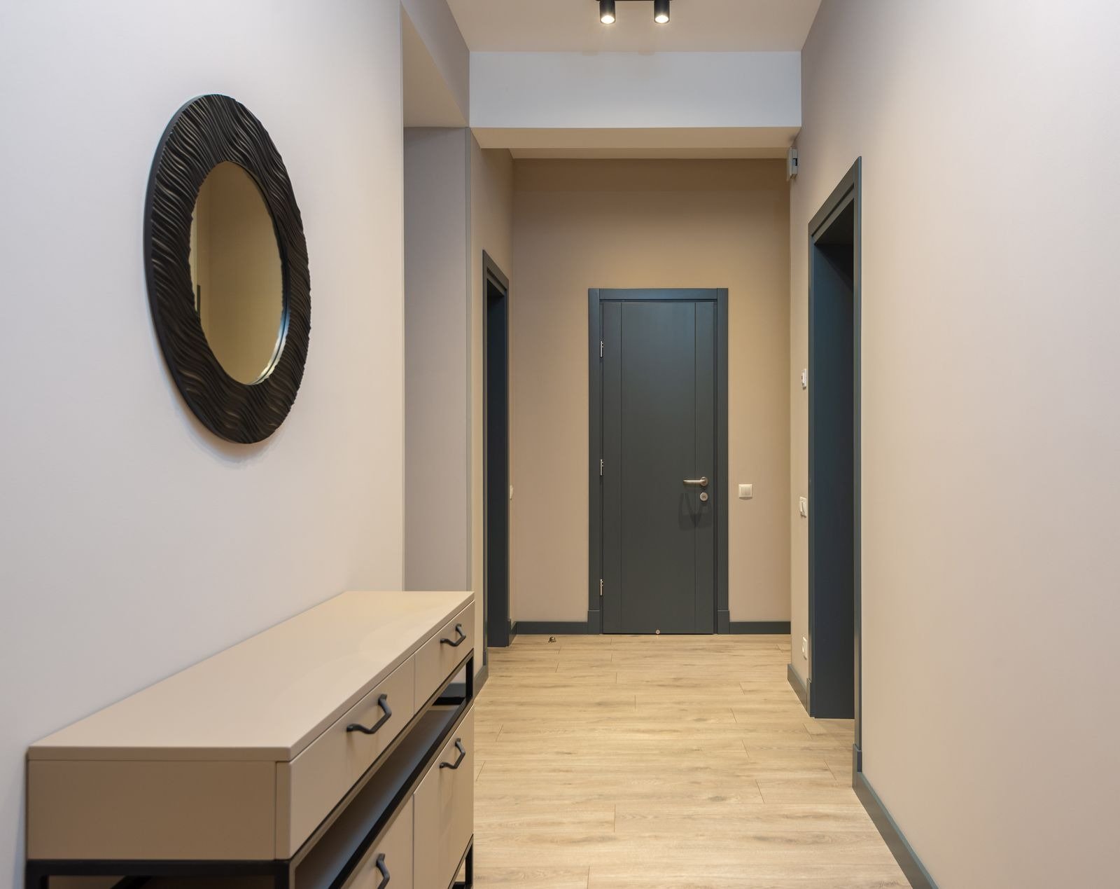 Bright hallway with a console table under a round mirror, a landing spot for keys and post
