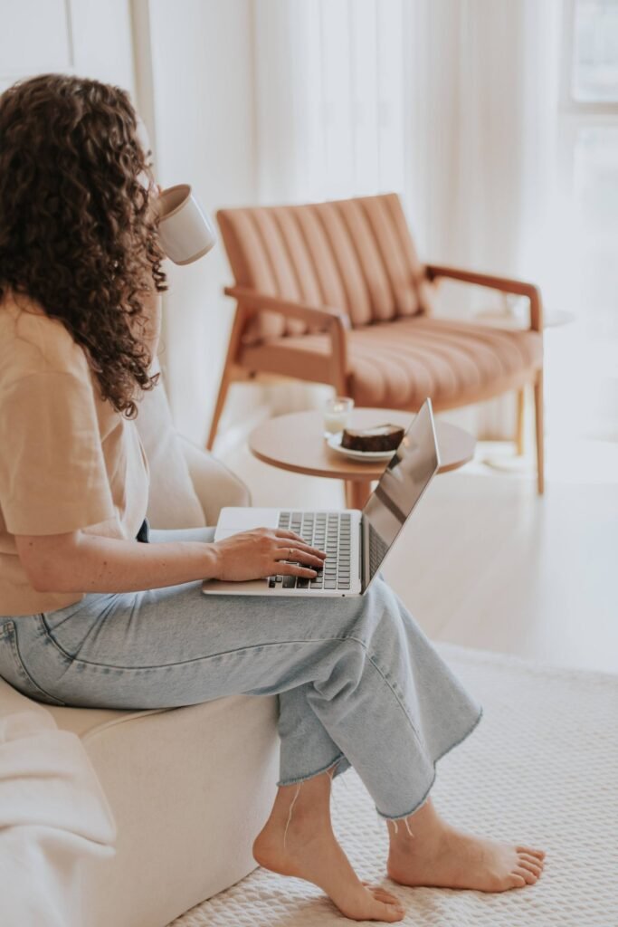 Woman working on a laptop in a warm, minimalist living room setting — work from home living room