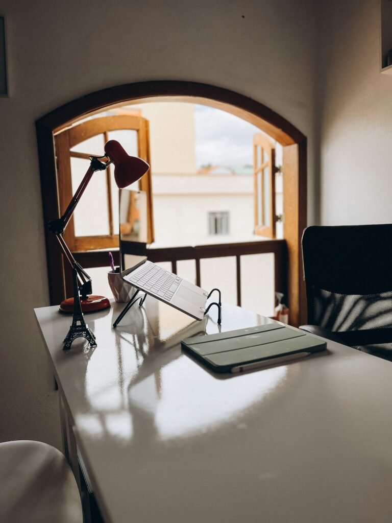 Small desk setup with laptop and lamp tucked in a cozy room by the window — small living room office