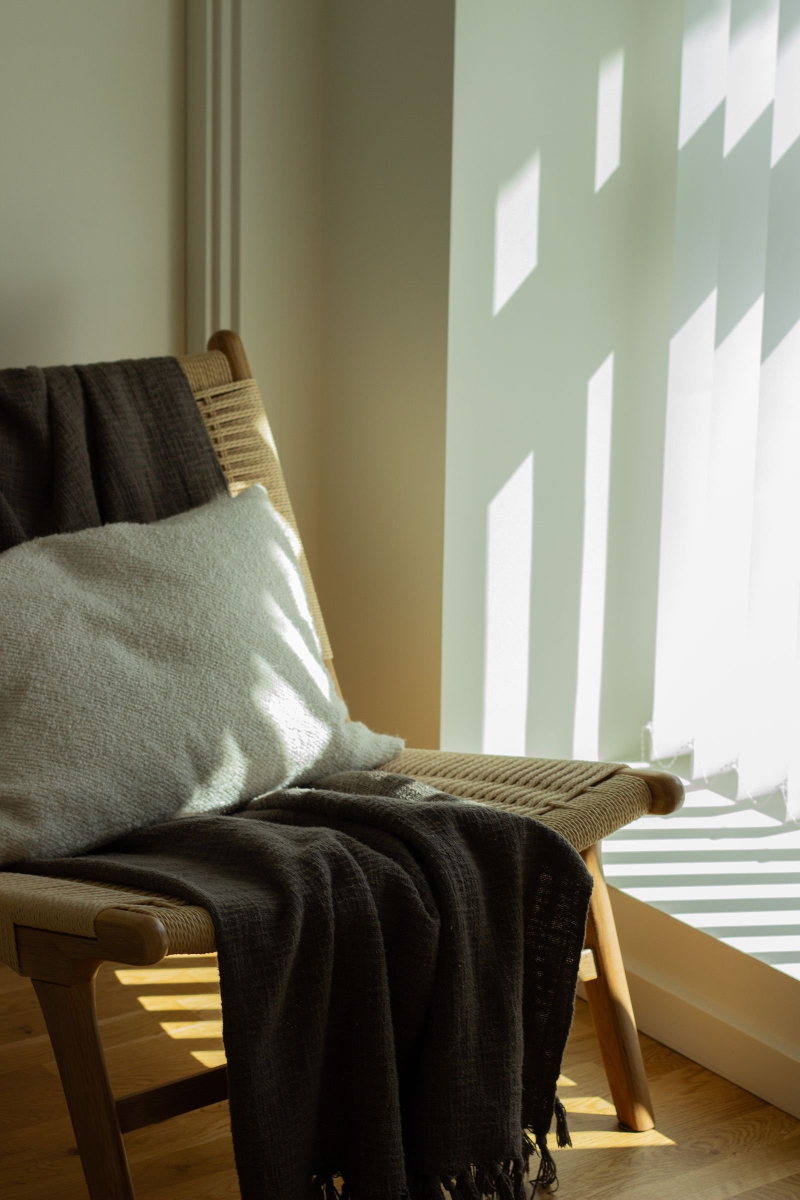 Warm sunlit corner with a wooden chair draped in textured throws