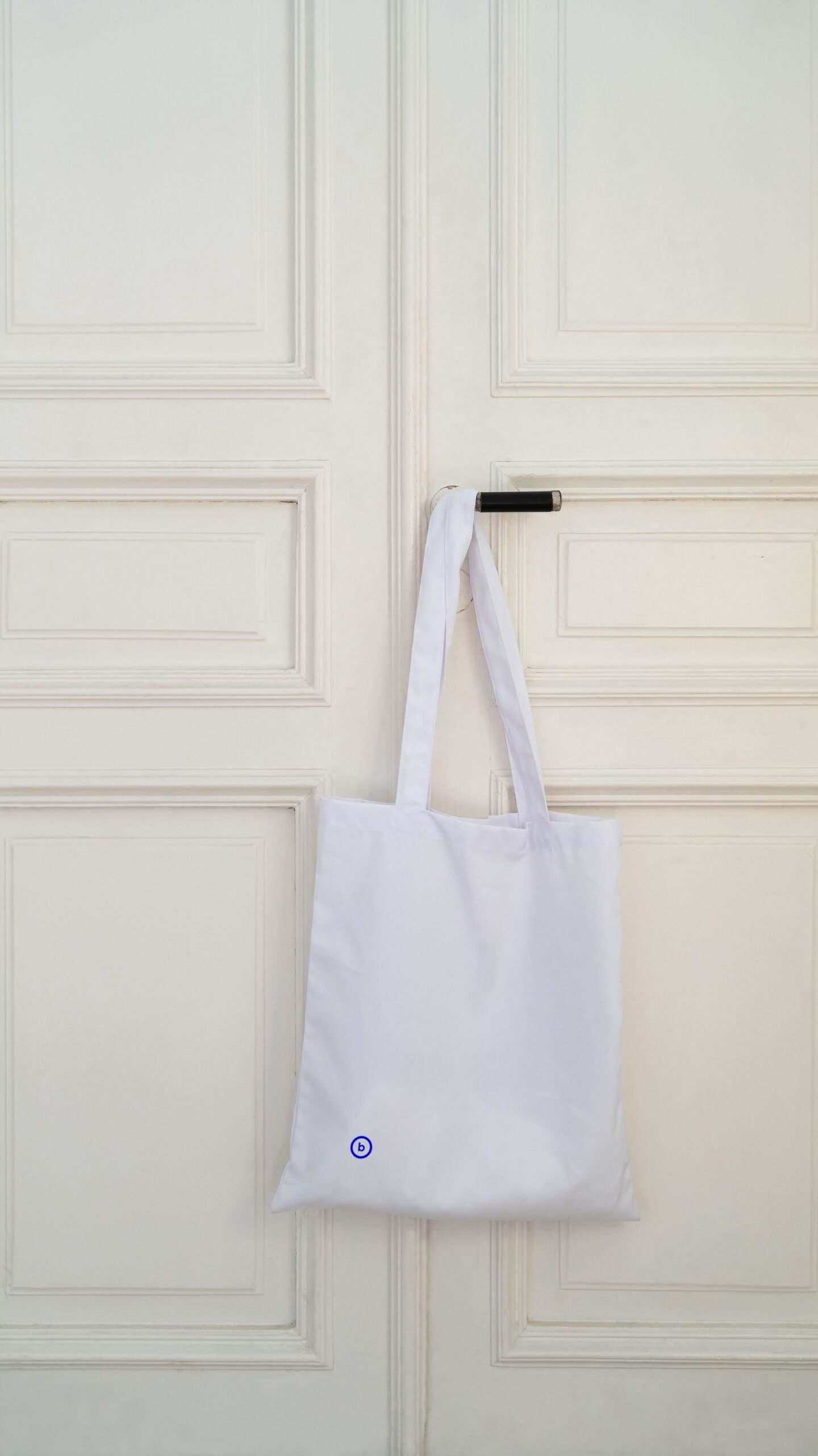 White tote bag hanging on a paneled door